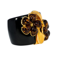 Chunky black acrylic cuff with amber crystal flower motif. Simon Harrison