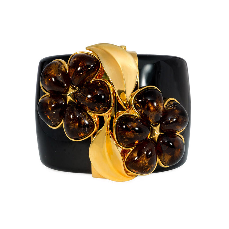 Chunky black acrylic cuff with amber crystal flower motif. Simon Harrison